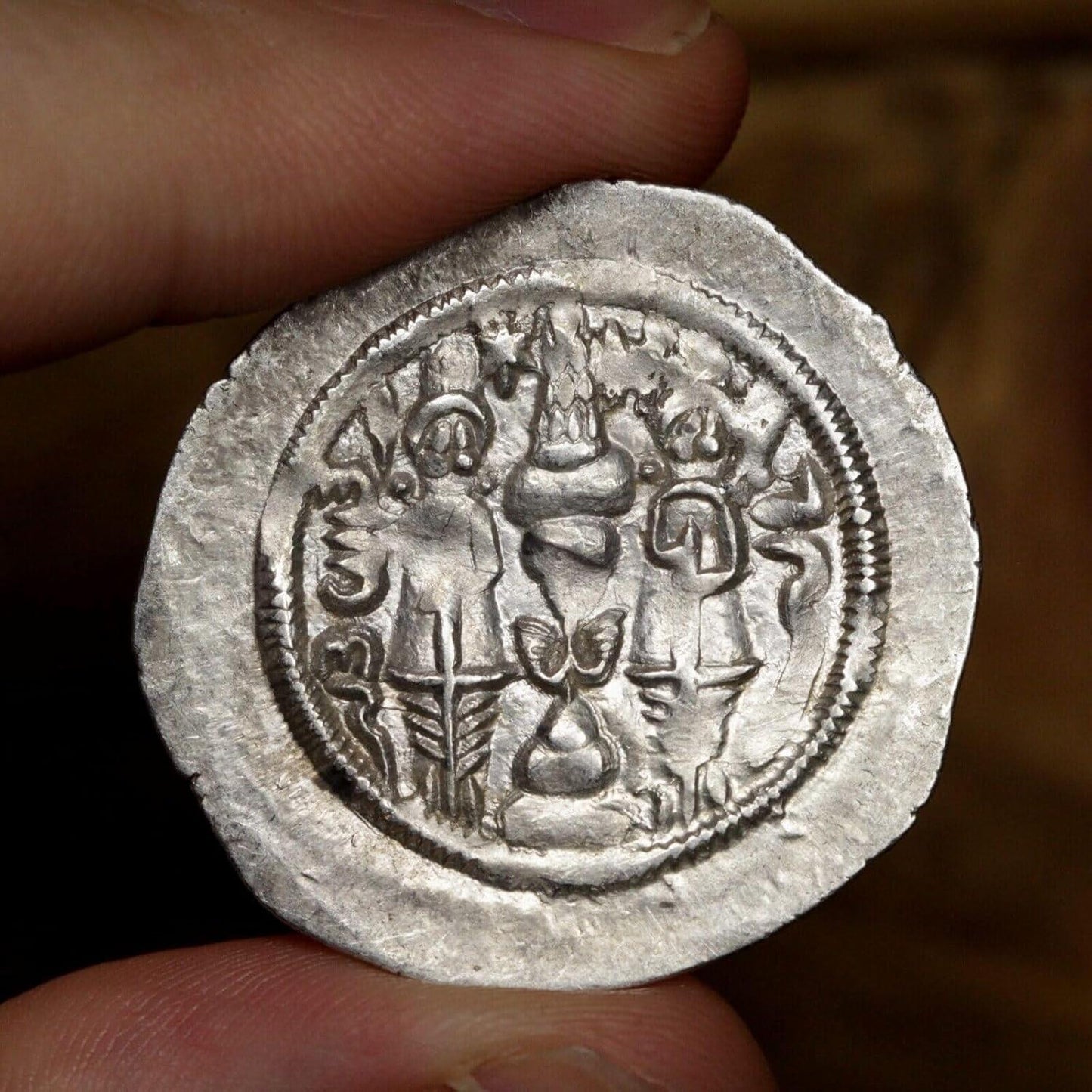 the reverse side of a sasanian silver drachm coin showing two Zoroastrian priests next to a fire altar
