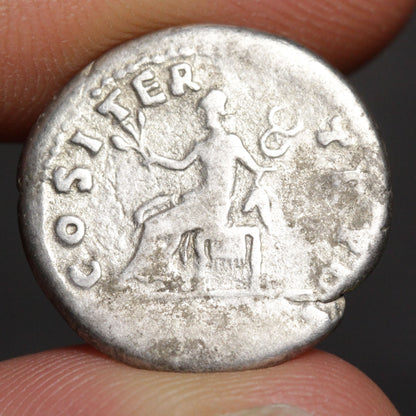 Ancient silver coin held between fingers with 'COSTIER' engraved