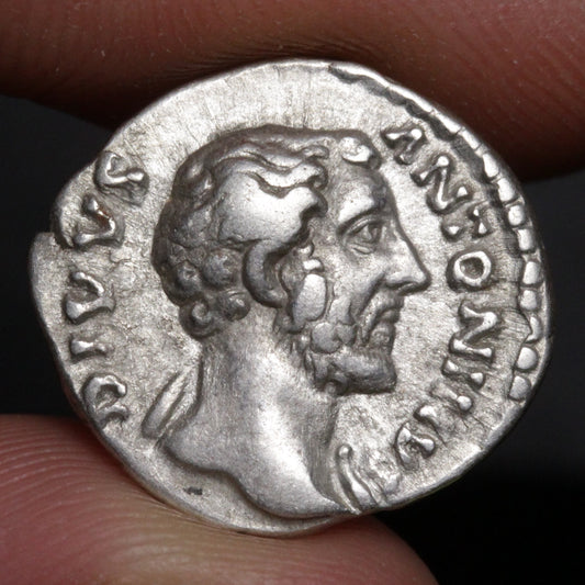 Ancient Roman coin with portrait of Antoninus Pius on a dark background