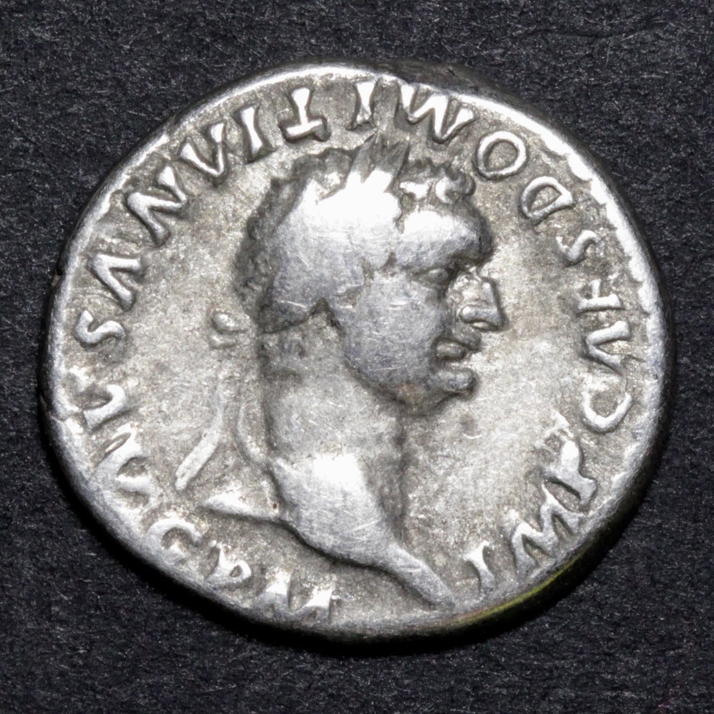 Ancient Roman coin with a profile of a emperor on a dark background