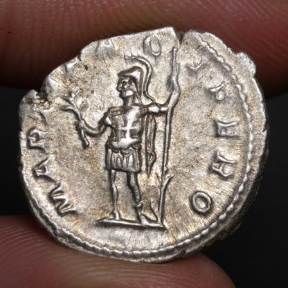 roman denarius being held between two fingers, design shows mars god of war