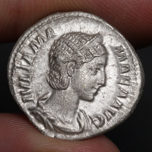 ancient roman coin being held between two fingers