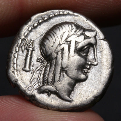 Ancient coin with a profile of a person and a candle, held between fingers.