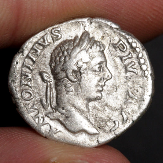 Ancient silver coin with profile of a Roman emperor held between fingers