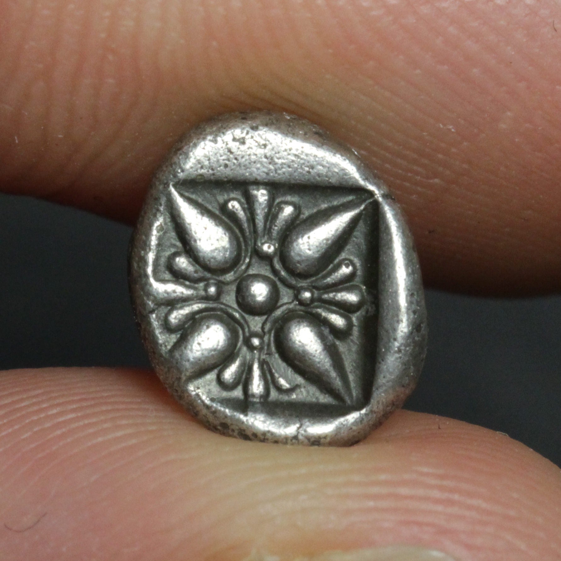 Small silver coin held between fingers against a neutral background