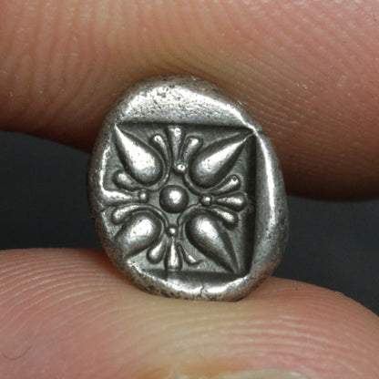 Small silver coin held between fingers against a neutral background