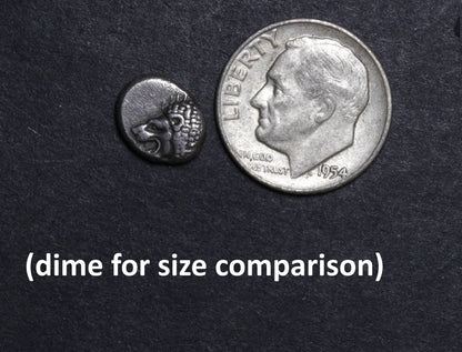 Small ancient coin and a dime for size comparison on a dark background