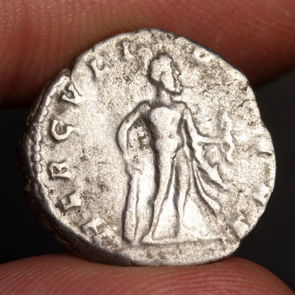 Ancient silver coin with a figure on it held between fingers
