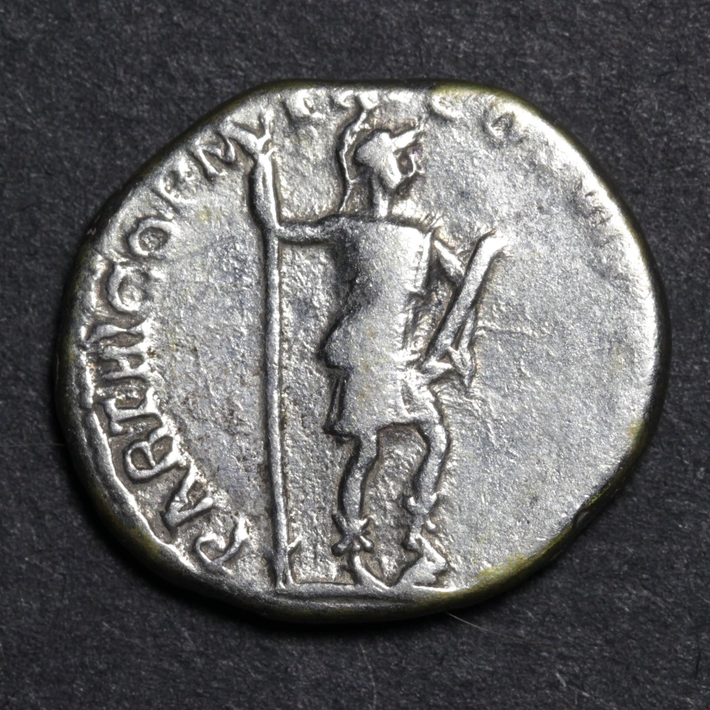 Ancient coin with a figure holding a spear on a dark background