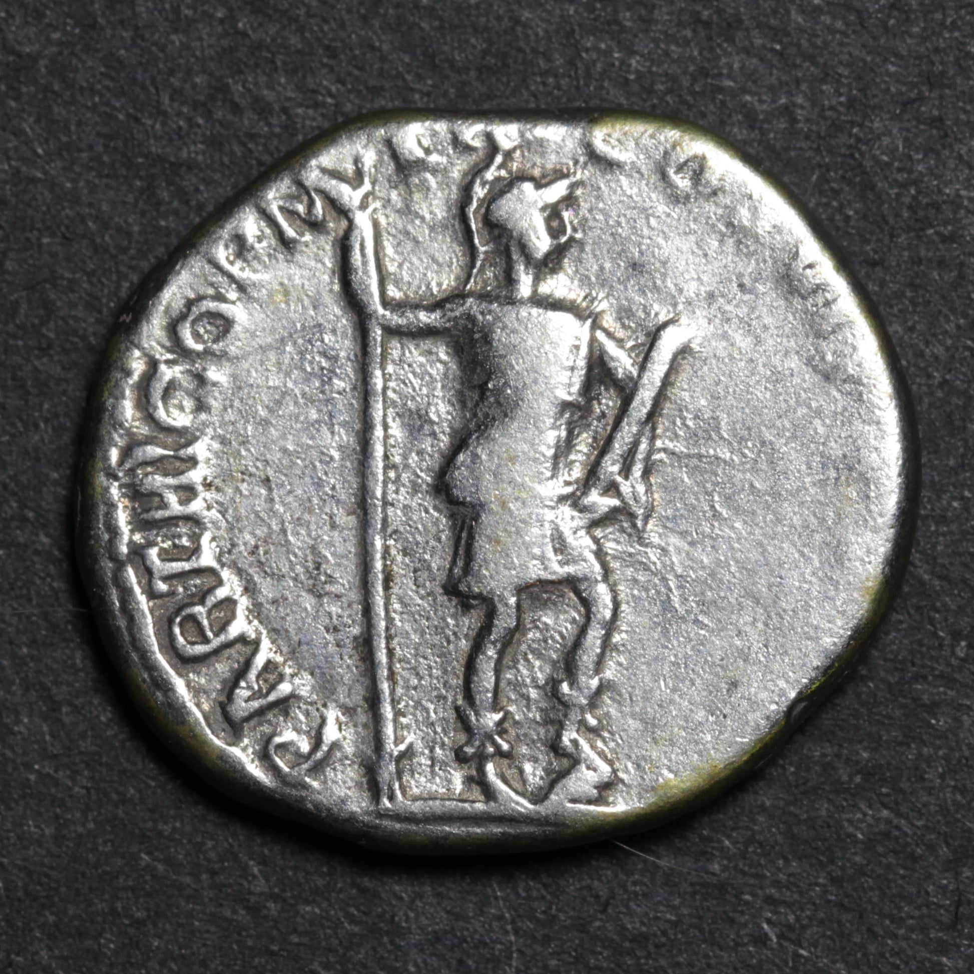 Ancient coin with a figure holding a spear on a dark background