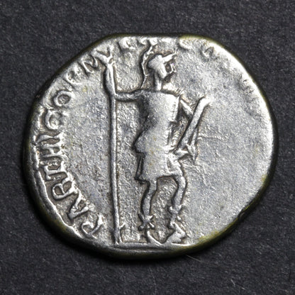 Ancient coin with a figure holding a spear on a dark background