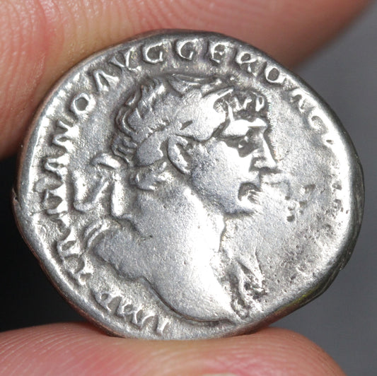 Ancient Roman silver coin held between fingers with a blurred background