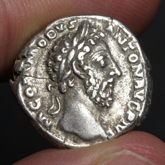 coin being held between two fingers with bust of bearded man