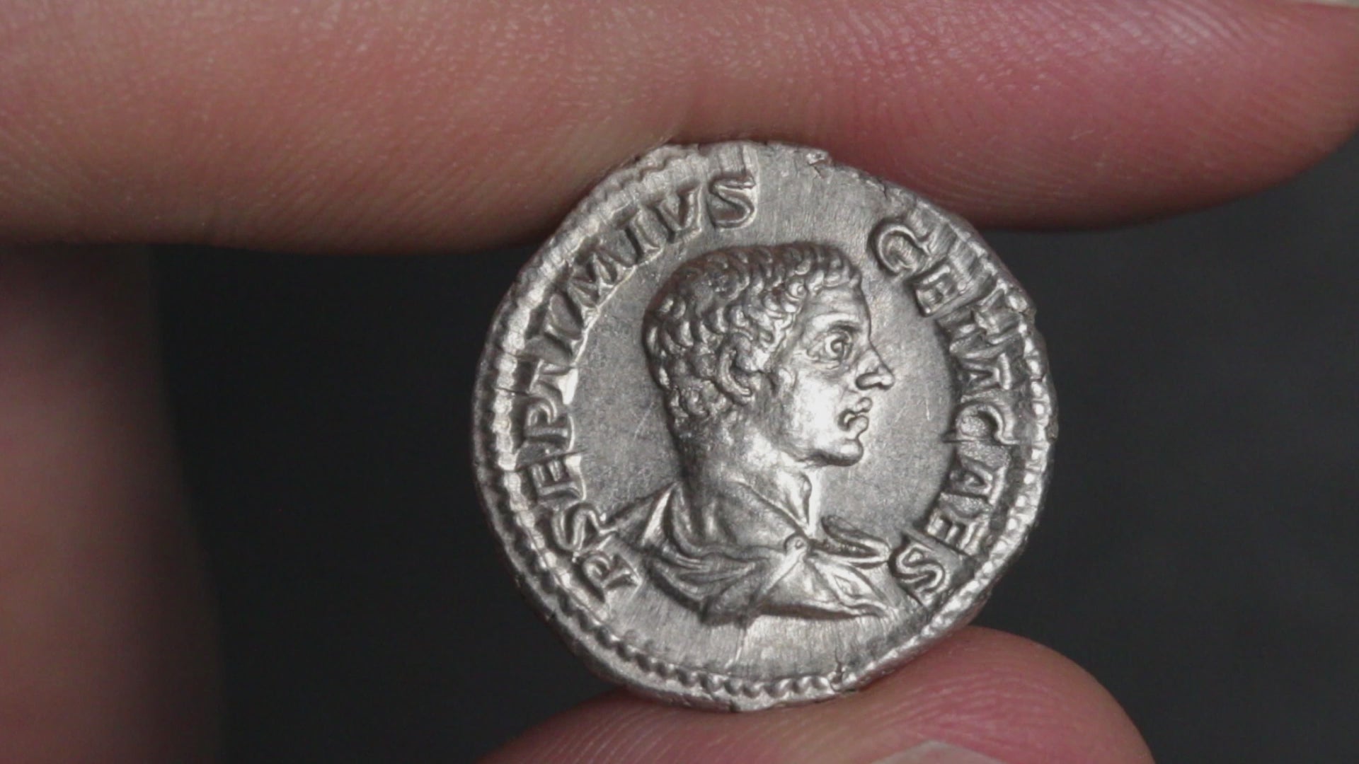 video of an ancient silver coin being rotated between two fingers to show both sides