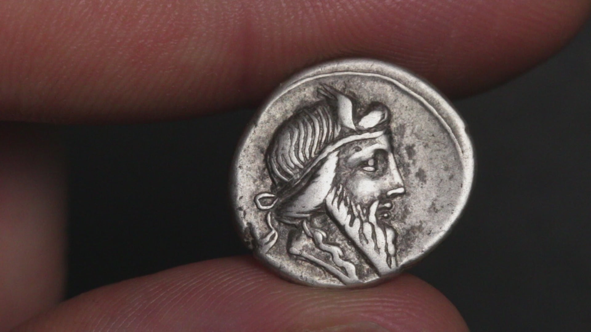 ancient coin being rotated between two fingers to show both sides
