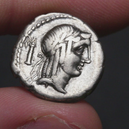 video of ancient coin being held between two fingers and rotated to show both sides