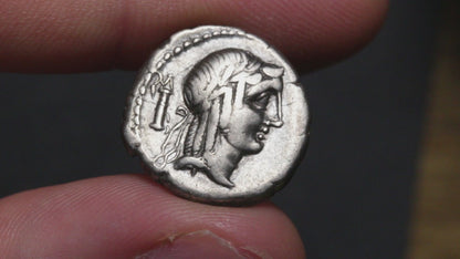 video of ancient coin being held between two fingers and rotated to show both sides